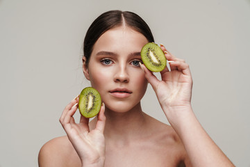 Image of beautiful shirtless woman posing with kiwi at camera