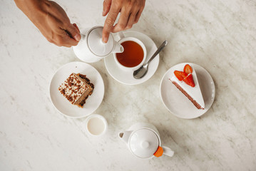Tea party with sweet desserts. Ceylon black tea with strawberry cheesecake. A metal teapot with pink tea in a restaurant. Hot drink on cafe table. Tea ceremony
