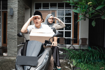 Obraz premium Young Muslim couple by motorcycle going home carrying lots goods to celebrating Eid mubarak in the village