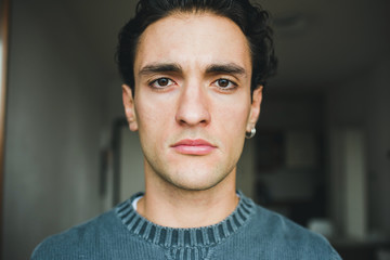 Portrait handsome young caucasian man indoors at home posing staring at camera