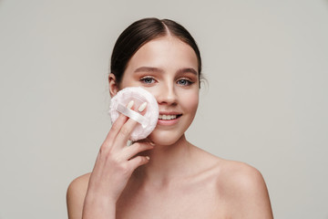 Image of pleased young shirtless woman using makeup pad and smiling