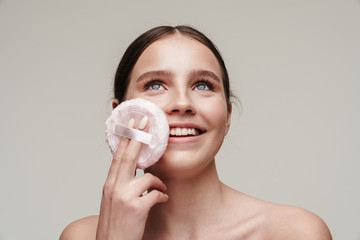 Image of pleased young shirtless woman using makeup pad and smiling