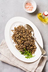 Quinoa for wholesome meal served in simple ceramic plate on old dark background. Top view.