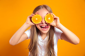 Funny little girl with citrus fruit on yellow background