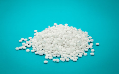 Large sprinkled handful of antiviral white pills on a blue background close-up