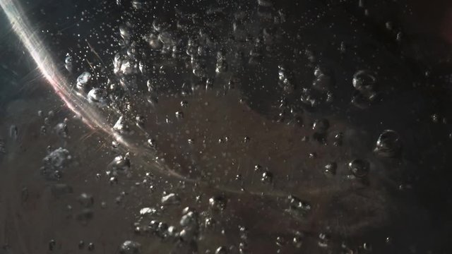 Intensive Boiling Water in a Steel Pan. Active boiling water in a stainless steel pan. Large bubbles come off the bottom and rise to the surface. Background - shiny bottom with scratches