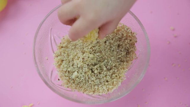 Little girl makes balls of cookie dough and dips nuts closer