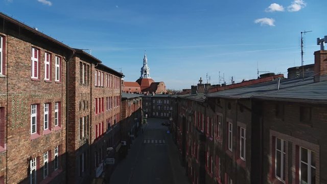 Old housing estate with antique red brick buildings and historic church in the background