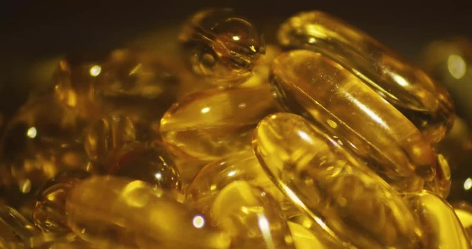 A close up macro shot of vitamin supplement containing cod liver oil reflecting light and liquid inside.