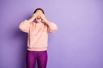 Photo of beautiful funny lady holding arms on eyes playing childish game hide and seek cheerful mood wear casual stylish fluffy sweater trousers isolated purple color background