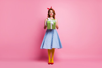 Full length photo of cheerful sweet pretty girl hold big green polka-dot bright gift box she get receive on 8-march anniversary wear blue stockings shoes isolated over pink color background