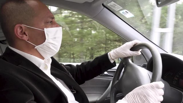 Senior adult wearing surgical gloves and mask driving in his car at empty street