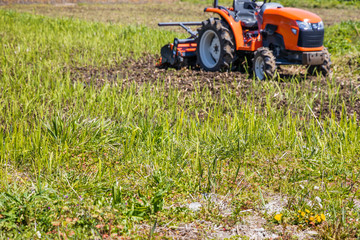 雑草の生えた畑とトラクター