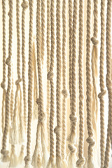 Ropes with knots. Bright home-made macrame interior decoration. Background with copy space.
