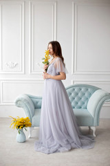 beautiful girl in a luxurious interior. restoration of antique furniture, interior design. a room with white plaster mouldings,a blue sofa upholstered in a blue velvet carriage tie.