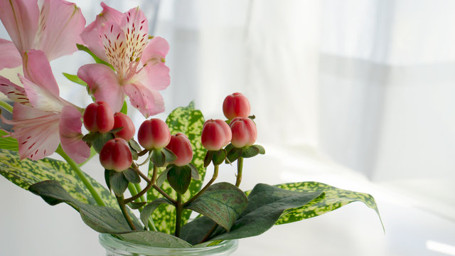 A small spring bouquet. Pink alstroemeria, red hipericum and gold dust dracaena.