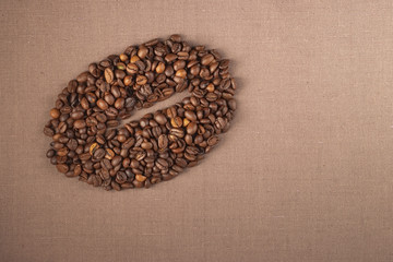 many coffee beans in the form of coffee bean on burlap background with copyspace