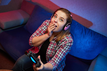Portrait of crazy playful Gamer enjoying Playing Video Games on Playstation indoors sitting on the sofa, holding Console Gamepad in hands, Xbox fans. Resting At Home, have a great Weekend