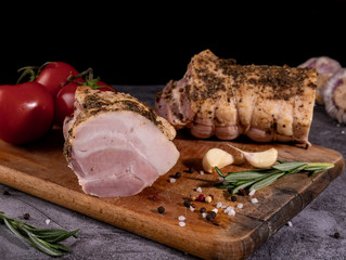 Tasty smoked ham on a wooden board with spices.