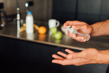 cropped view of man holding bottle with hand sanitizer