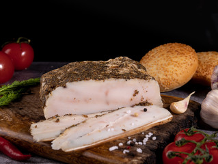 Pork lard with spices on a wooden board on a dark background