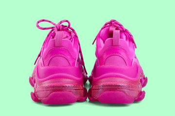 Pair of new trendy fuchsia sneakers isolated on a light green background with shadow. Rear view.