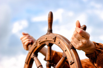 Steering hand wheel ship on sky background, hand hold hand wheel