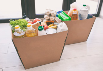 The full cardboard eco box with products from the grocery store on the floor at home near the door