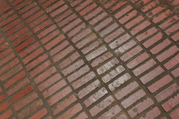 Background of red brick receding into a corner, glazed surface with thick mortar, horizontal aspect