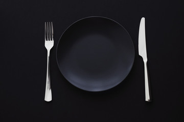 Empty plates and silverware on black background, premium tableware for holiday dinner, minimalistic...