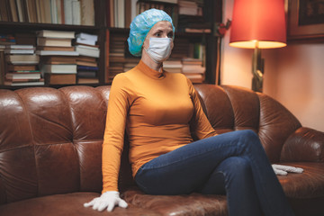 Woman with protective antiviral mask sitting at home in isolation / quarantine.