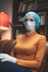 Woman with protective antiviral mask sitting at home in isolation / quarantine.