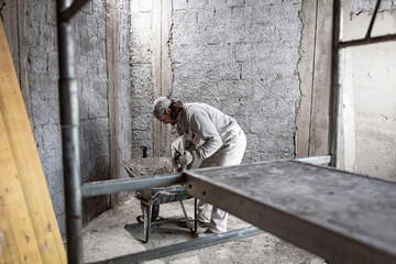 Real construction worker making a wall inside the new house.