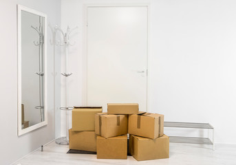 Pile of cardboard boxes in white minimalist white home hallway. Lot of room for text.