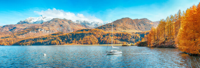 Picturesque autumn views of Sils Lake (Silsersee) with small white yacht