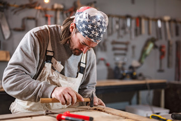 Male carpenter working on old wood in a retro vintage workshop.