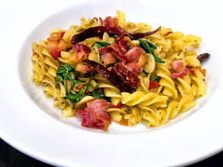 Spicy Fusilli spaghetti stir fried with grilled bacon hotdog and sausage, Italian food cooked with basil and chili pepper in the white plate. Delicious Thai-Italian food restaurant and cuisine style.