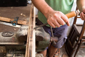Male carpenter working on old wood in a retro vintage workshop.