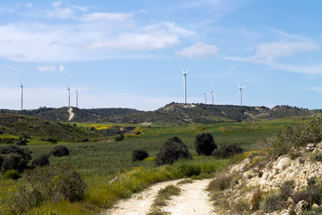 Rural landscape with country road, fields and wind turbine towers 