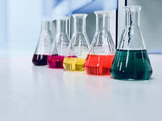 The Erlenmeyer or Conical flask on bench laboratory, with colorful solvent solution from titration experiment, acidity, alkalinity, and total hardness analysis compounding in wastewater sample. - obrazy, fototapety, plakaty