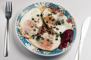 A plate with fried eggs, sprinkled with pepper and green onions.