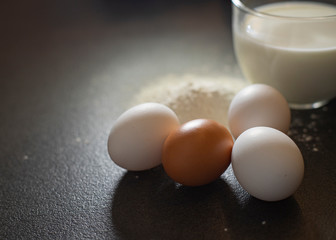 Ingredients for baking on a black background. Ingredients for the dough. Eggs, milk, flour.
