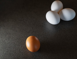 White eggs and brown eggs on a black background. Eggs on table. 