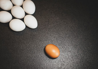 White eggs and brown eggs on a black background. Eggs on table. 