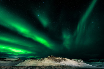 Green Aurora borealis streamers, northern Iceland with snow covered psuedo craters on the shores of...