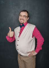 Funny thick teacher or business man showing thumbs up on blackboard