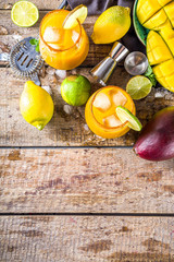 Summer tropic mexican cold cocktail. Mango margarita cocktail, with tequila, lime, lemon, hot chili jalapeno peppers. Wooden background with bar party utensils copy space