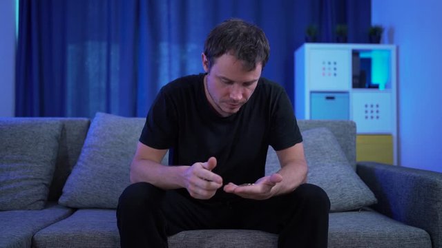 a man sitting counting money on the sofa, very few of them