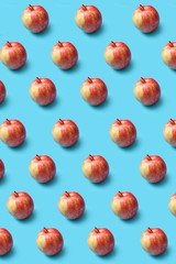 Creative pattern from fresh organic red apples on a blue background.