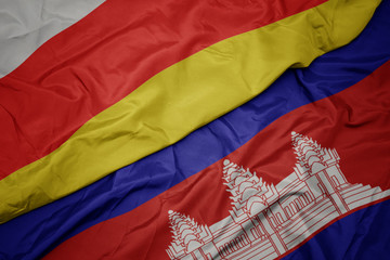 waving colorful flag of cambodia and national flag of south ossetia.